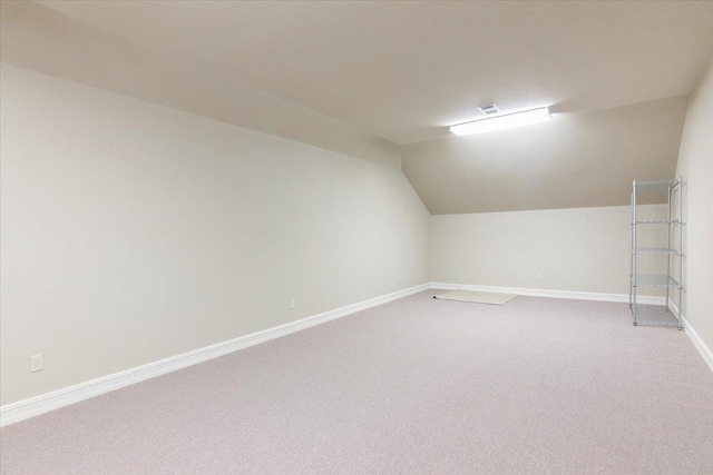 bonus room with light colored carpet, vaulted ceiling, visible vents, and baseboards