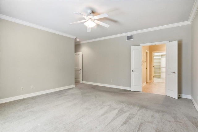 carpeted empty room with ceiling fan, ornamental molding, visible vents, and baseboards