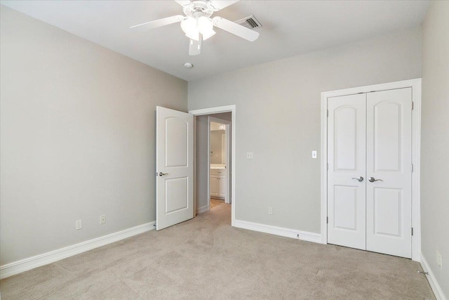 unfurnished bedroom with a closet, light colored carpet, visible vents, and baseboards