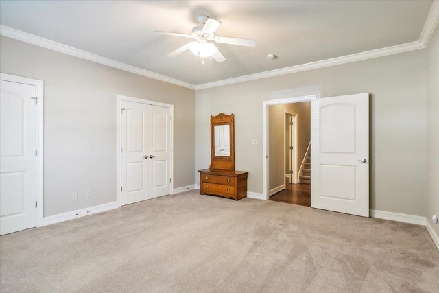 unfurnished bedroom featuring baseboards, carpet floors, ceiling fan, and crown molding