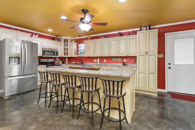 kitchen with a breakfast bar, cream cabinets, a center island, and stainless steel appliances