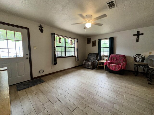 sitting room featuring a ceiling fan, wood finished floors, a textured ceiling, and visible vents