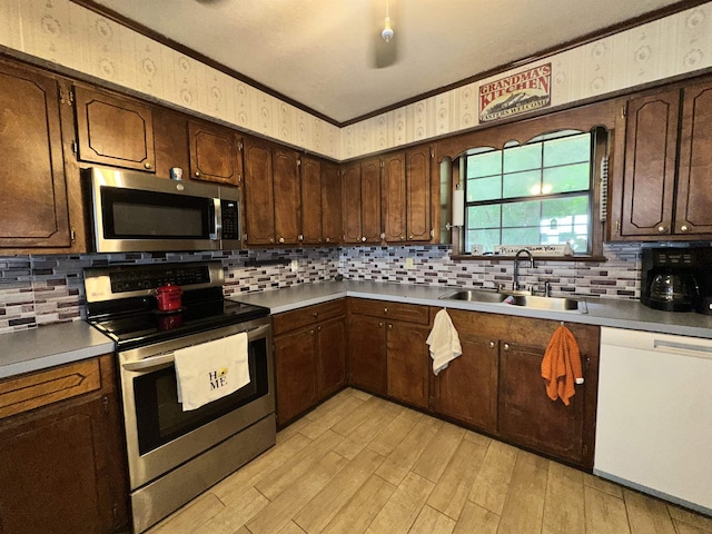 kitchen featuring a sink, ornamental molding, wallpapered walls, and stainless steel appliances