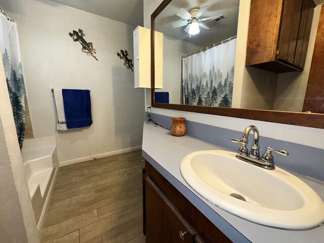 bathroom with a shower with shower curtain, baseboards, wood finished floors, vanity, and a ceiling fan