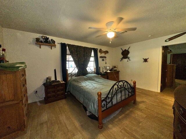 bedroom featuring visible vents, a textured ceiling, wood finished floors, and a ceiling fan