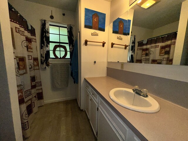 full bath featuring vanity, curtained shower, baseboards, and wood finished floors