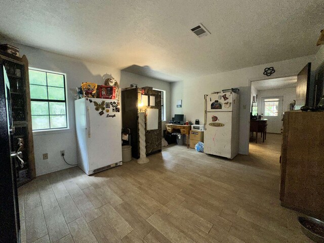 interior space with a textured ceiling, light wood finished floors, and visible vents