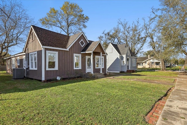 view of front of home with a front lawn, central air condition unit, board and batten siding, and a shingled roof