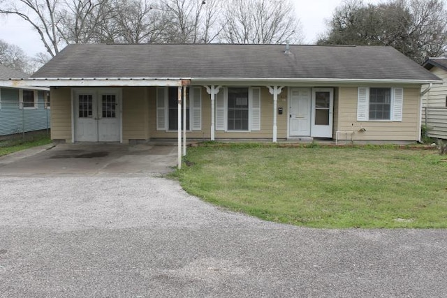 ranch-style home featuring covered porch, aphalt driveway, and a front yard