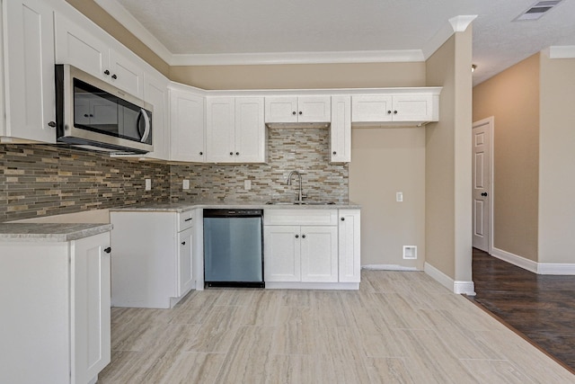 kitchen with sink, stainless steel appliances, tasteful backsplash, crown molding, and white cabinets