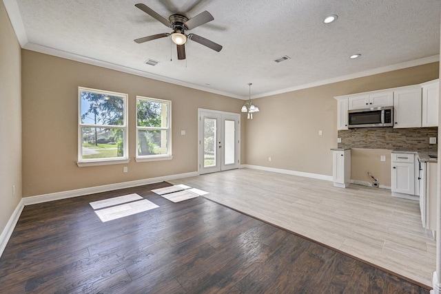 interior space with french doors, crown molding, light hardwood / wood-style floors, a textured ceiling, and ceiling fan with notable chandelier