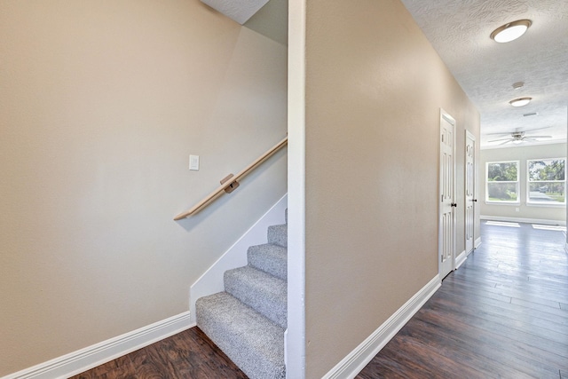 stairs with hardwood / wood-style flooring, ceiling fan, and a textured ceiling