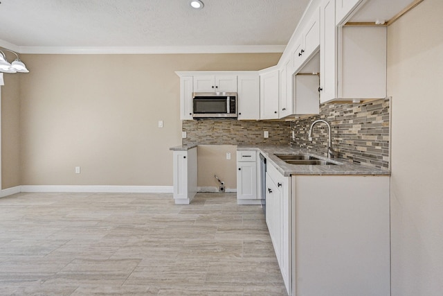 kitchen with tasteful backsplash, white cabinetry, crown molding, and sink