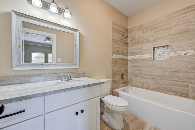 full bathroom featuring vanity, ceiling fan, tiled shower / bath combo, toilet, and a textured ceiling