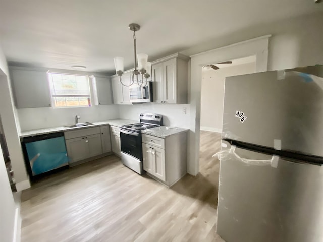 kitchen featuring gray cabinetry, sink, hanging light fixtures, stainless steel appliances, and light hardwood / wood-style floors