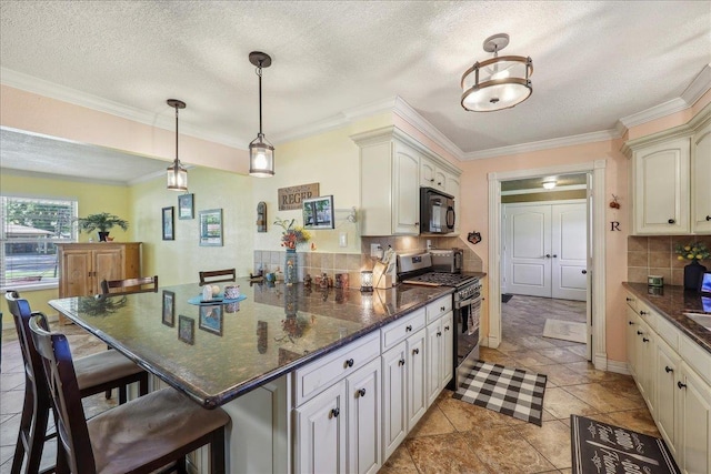 319 Dixie Dr, Bridge City, TX 77611 - kitchen featuring stainless steel range with gas stovetop, black microwave, a peninsula, a breakfast bar, and ornamental molding