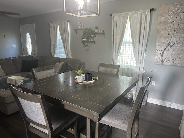 dining space with plenty of natural light, dark wood-type flooring, and a notable chandelier