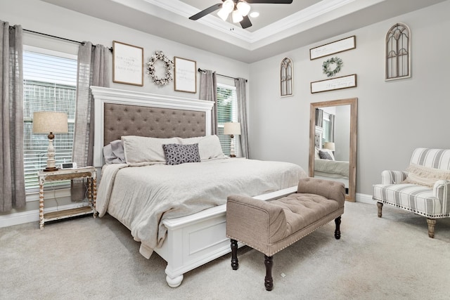 carpeted bedroom with ceiling fan, crown molding, and a raised ceiling