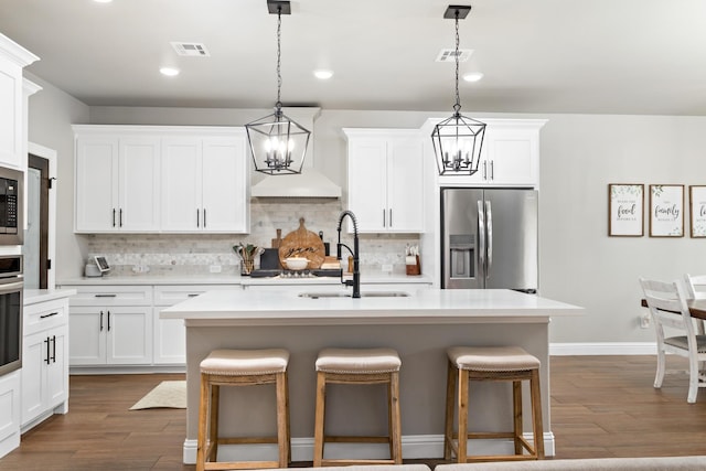 kitchen featuring pendant lighting, sink, white cabinets, an island with sink, and stainless steel appliances