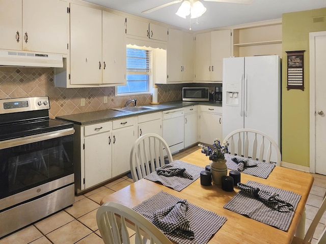 kitchen featuring a sink, appliances with stainless steel finishes, under cabinet range hood, and dark countertops