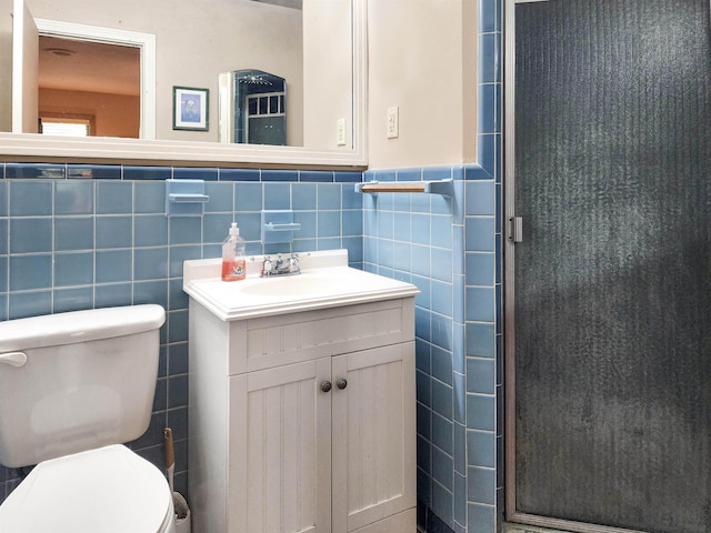 bathroom with vanity, tile walls, a stall shower, and toilet