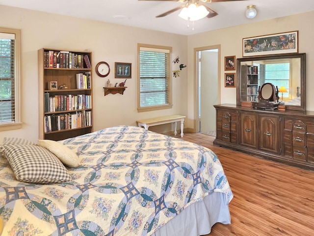 bedroom featuring ceiling fan, multiple windows, and light wood-style flooring