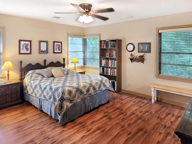 bedroom featuring baseboards, a ceiling fan, wood finished floors, and visible vents