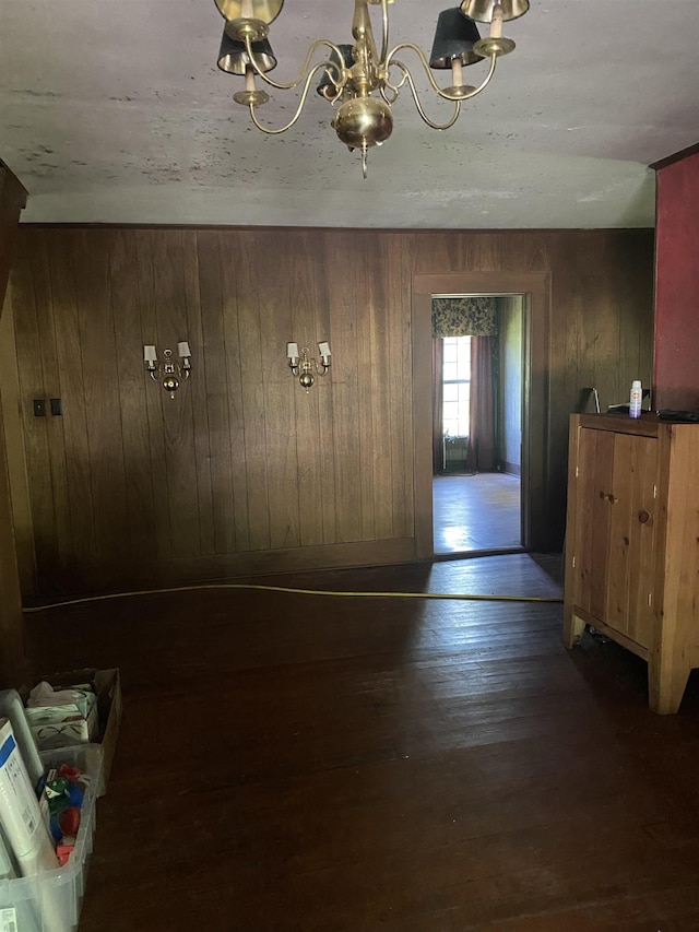 foyer featuring wood walls, dark hardwood / wood-style flooring, and an inviting chandelier