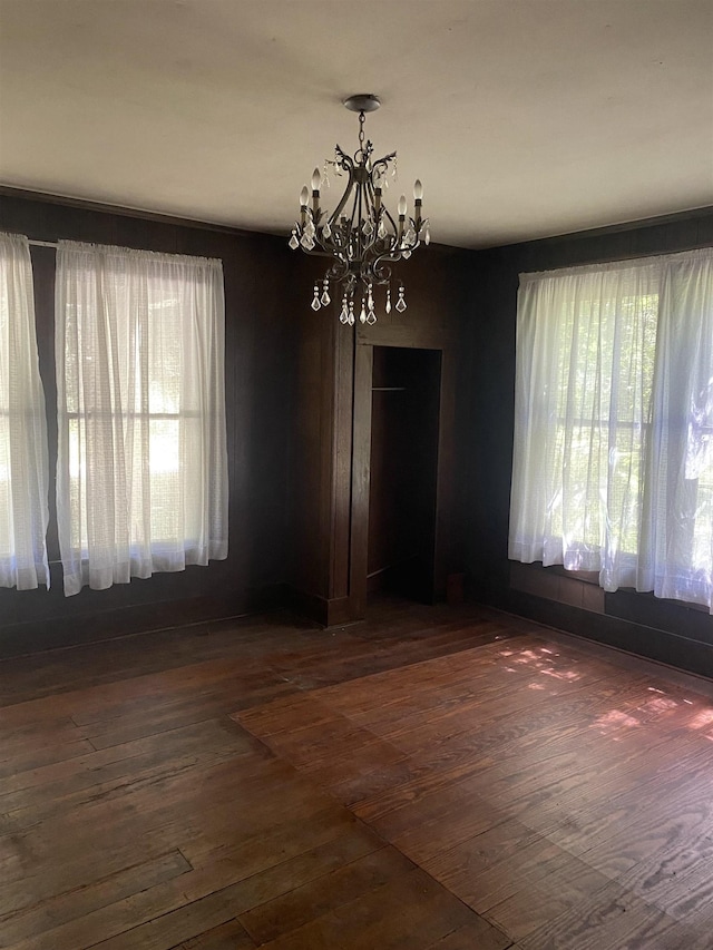 unfurnished dining area with dark hardwood / wood-style flooring and a chandelier