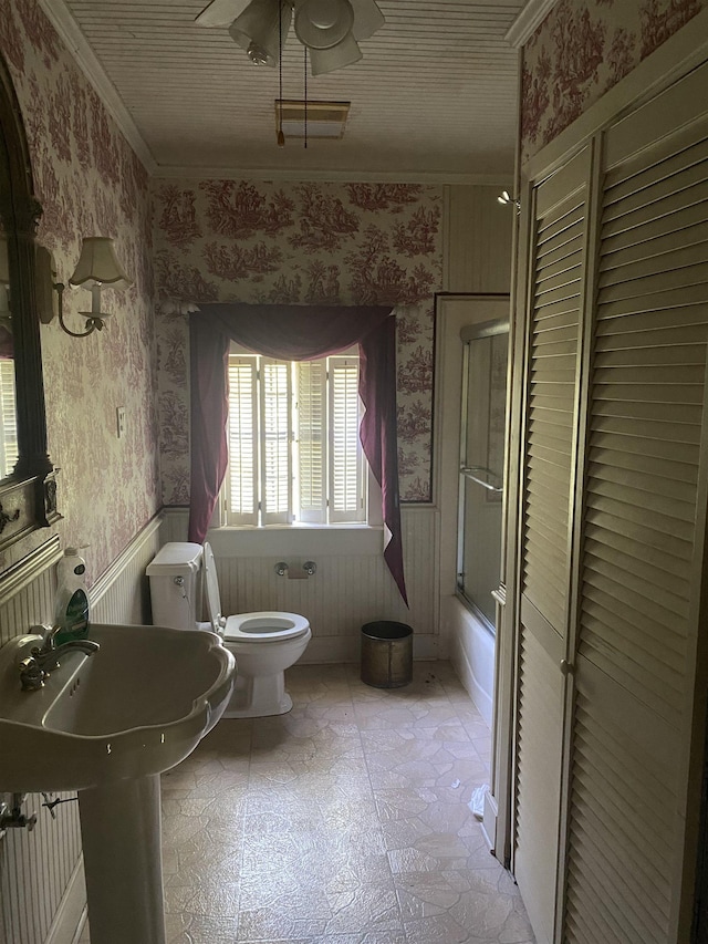 bathroom featuring toilet, shower / bath combination with glass door, crown molding, and a bidet