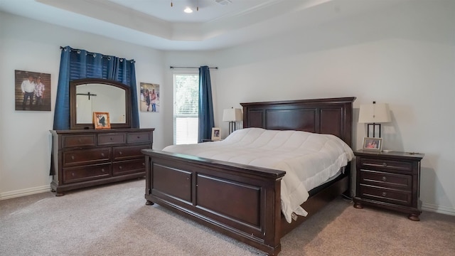 carpeted bedroom with a tray ceiling