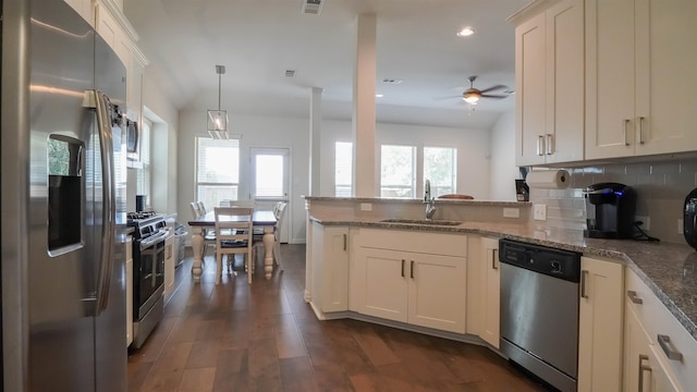 kitchen with stainless steel appliances, ceiling fan, sink, pendant lighting, and stone countertops