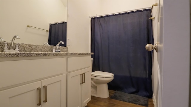 bathroom featuring a shower with shower curtain, hardwood / wood-style floors, vanity, and toilet