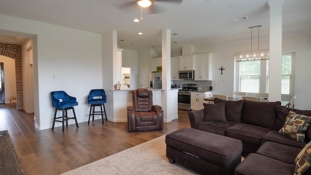 living room featuring ceiling fan with notable chandelier and dark hardwood / wood-style floors