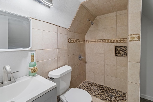 bathroom featuring a tile shower, vanity, toilet, and tile walls