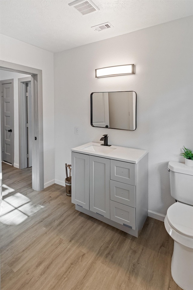 bathroom featuring toilet, vanity, and hardwood / wood-style flooring