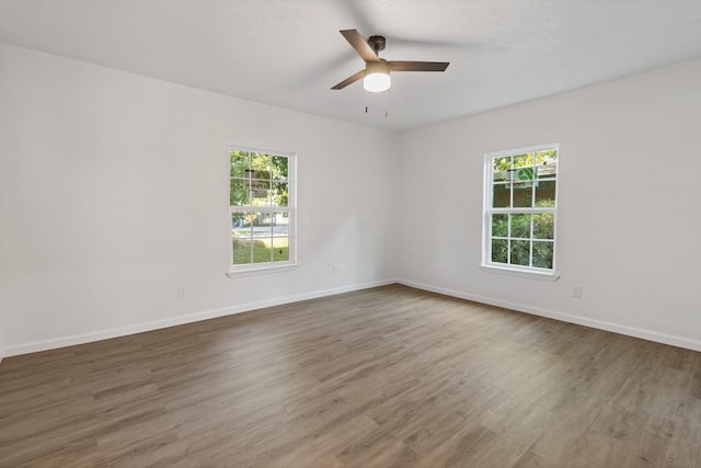 empty room with a wealth of natural light, ceiling fan, and hardwood / wood-style flooring