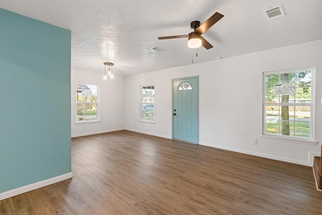 interior space with ceiling fan with notable chandelier, dark hardwood / wood-style floors, and a textured ceiling