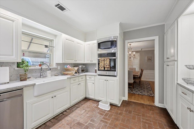 1550 Belvedere Dr, Beaumont, TX 77706 - kitchen featuring appliances with stainless steel finishes, a sink, a chandelier, brick patterned floors, and decorative backsplash