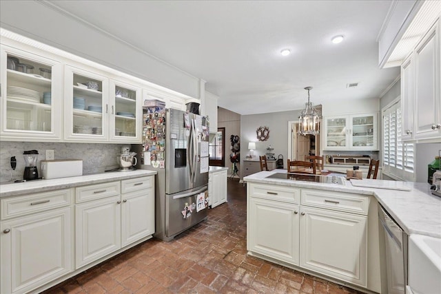 1550 Belvedere Dr, Beaumont, TX 77706 - kitchen featuring stainless steel appliances, brick floors, a peninsula, a chandelier, and white cabinetry