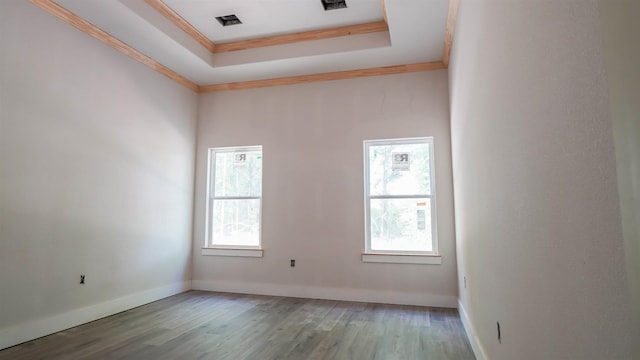 spare room with baseboards, wood finished floors, a tray ceiling, and ornamental molding
