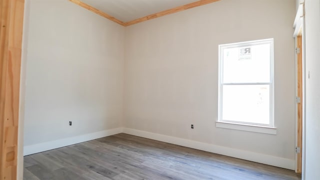 unfurnished room featuring wood finished floors, crown molding, and baseboards