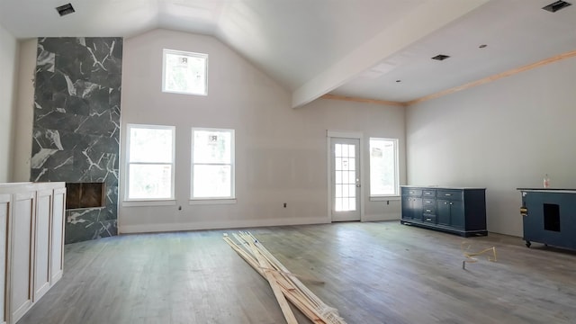 unfurnished living room featuring visible vents, wood finished floors, and lofted ceiling