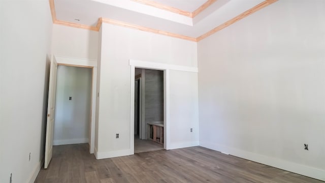unfurnished bedroom featuring ensuite bath, baseboards, ornamental molding, and wood finished floors