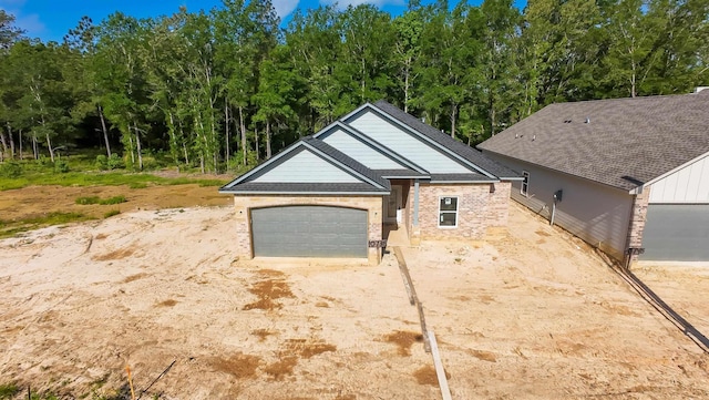 exterior space featuring brick siding, an attached garage, a shingled roof, and driveway