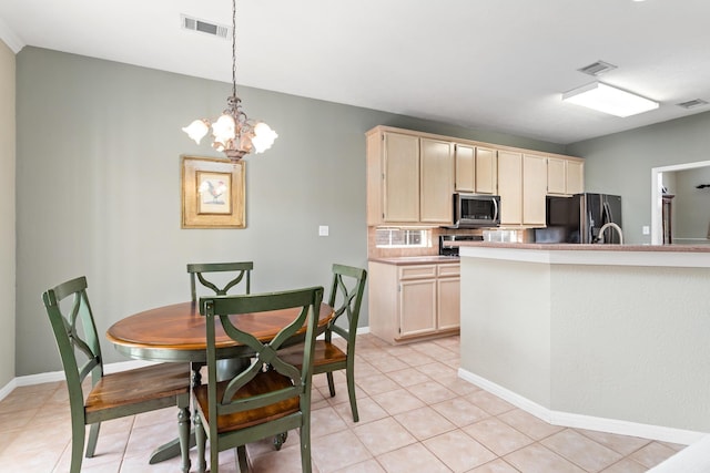 kitchen featuring hanging light fixtures, light tile patterned flooring, black fridge, and a chandelier