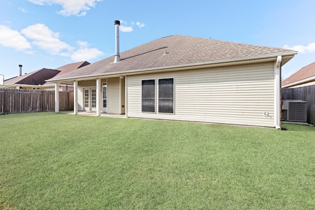 rear view of property featuring central AC unit and a lawn