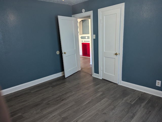 unfurnished bedroom with dark hardwood / wood-style floors and a textured ceiling