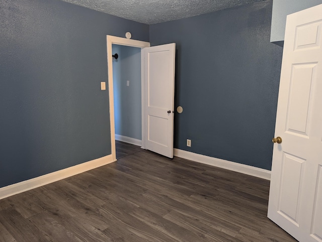 empty room with dark hardwood / wood-style flooring and a textured ceiling