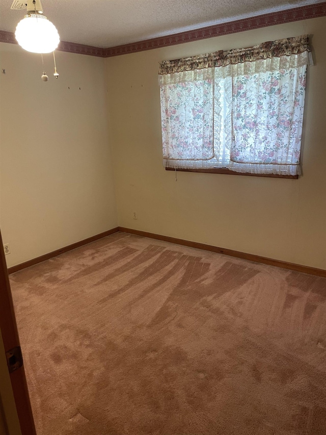 empty room with baseboards, light colored carpet, and a textured ceiling